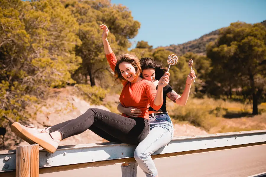 Women with lollipops sitting on guard rail